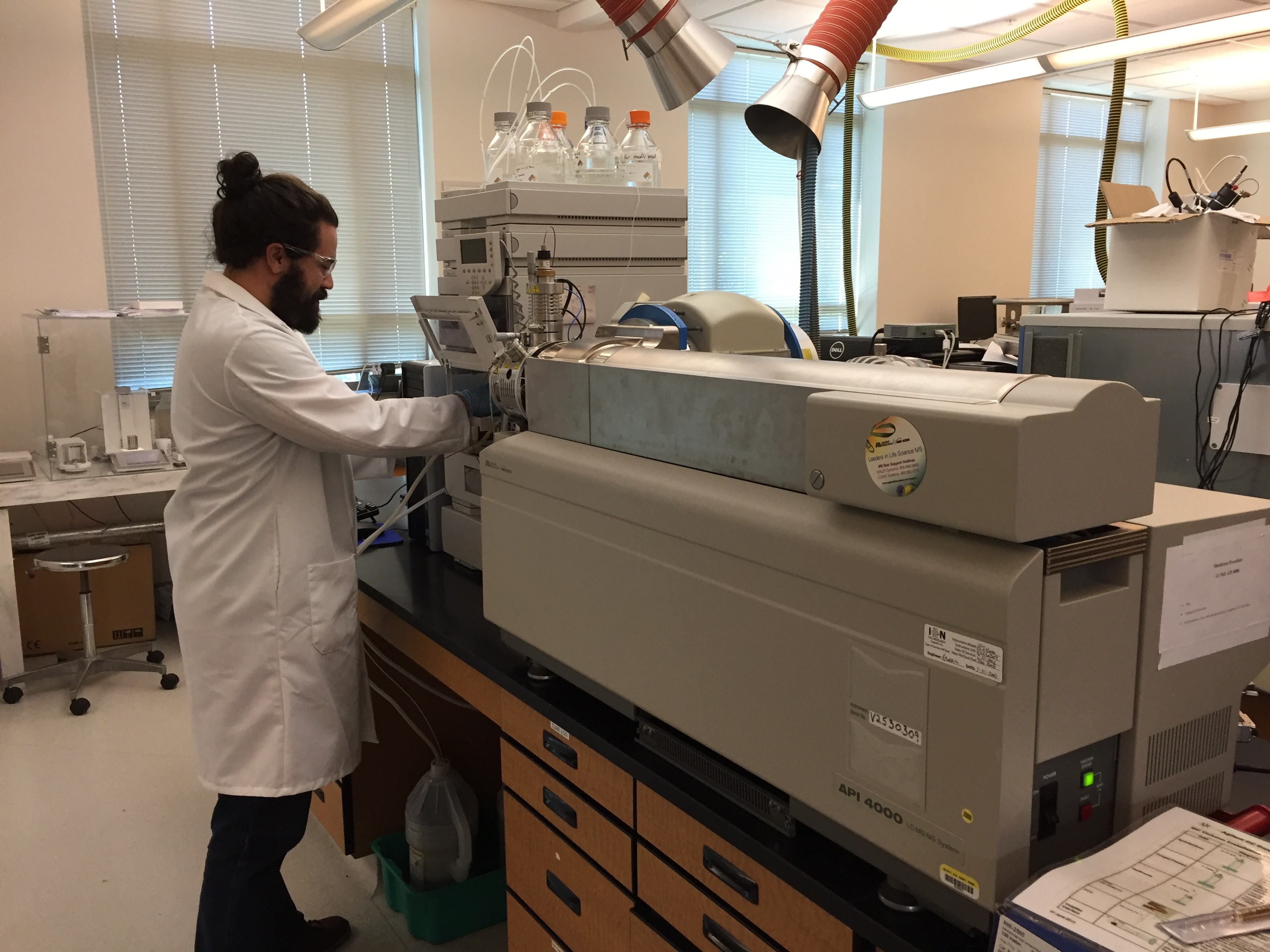 Man in lab coat putting sample into a large machine
