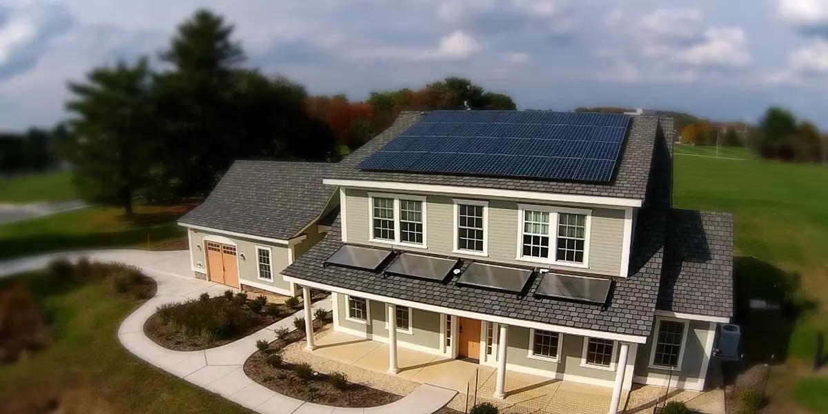 A newly built two-story home with an attached garage has solar panels on the roof.