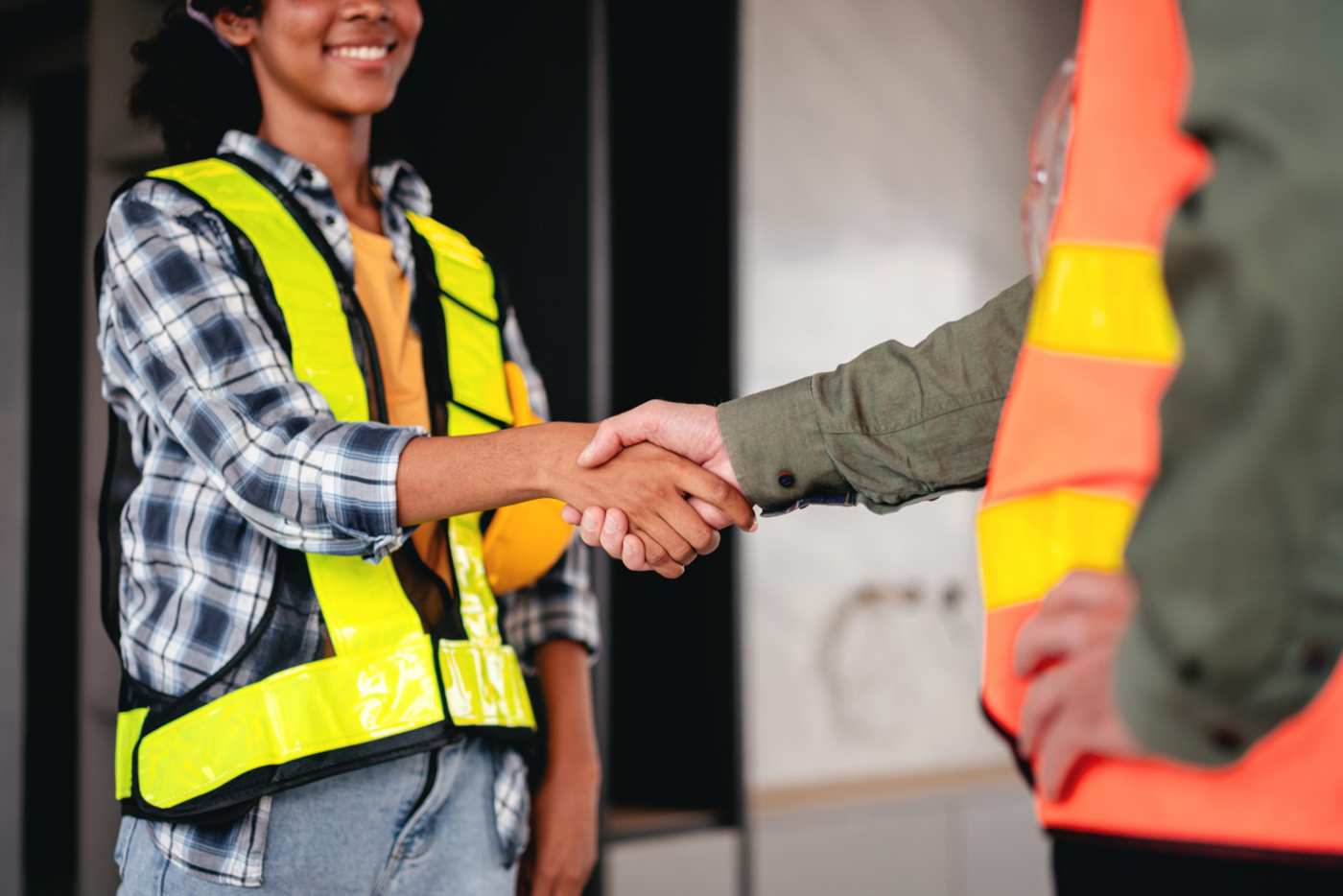 two manufacturing workers happily shake hands 
