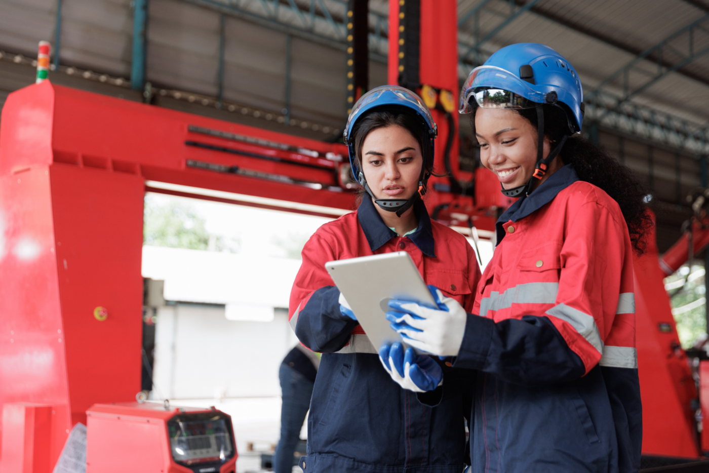 two female engineers wearing safety gear and collaborating in a factory