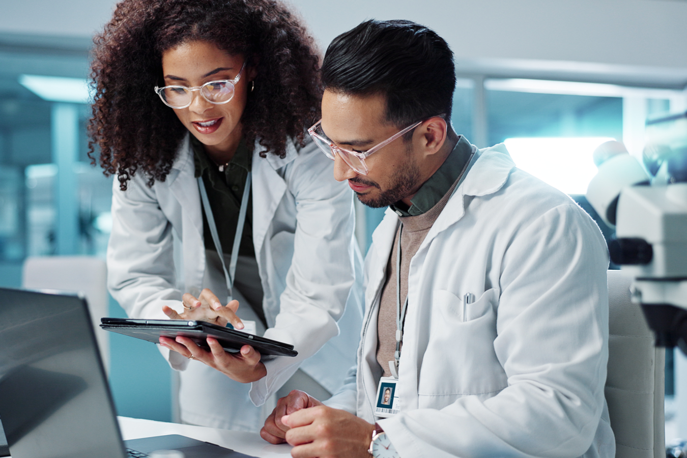 two researchers, working in a lab, happily collaborate at a computer 