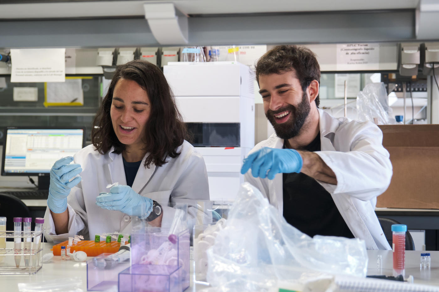 Two smiling graduate students work together at a lab bench