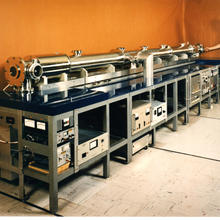 Long metal cylinder on a table with a man standing at the far end.