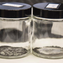 Two clear bottles. Black dust lies at the bottom of both.