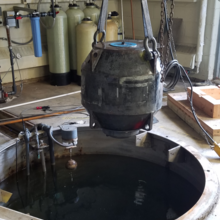 A large metal ball is pulled out of a pit with an overhead pulley