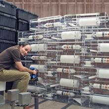 A man sits in front of a series of clear cases