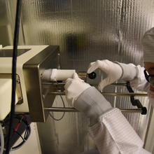 A woman in a clean suit loads a sample into a microscope