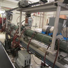 Long greenish metal tube surrounded by machinery