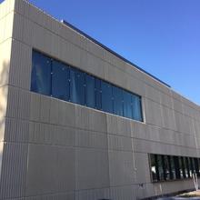 Exterior view of building addition, brown wall with dark windows