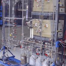 A rack hold four square boxes and four metal canisters, attached with tubing.