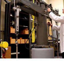 Blonde woman in white lab coat working on equipment