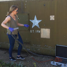 Woman in safety goggles operates an instrument housed in an aluminum briefcase