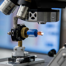 A device holds a sample under a microscope.