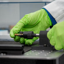 Person wearing green gloves positions bullet in holder.