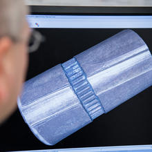 The side of a man's face as he looks at a bullet model on a screen.