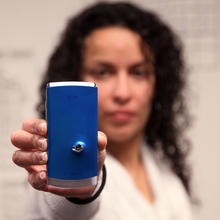 A woman holds a cellphone with a bullet hole in it.