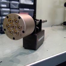 Bronze metal cylinder clamped sideways on a lab bench.