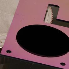 A flat pink device with a round black patch lies over a quarter.