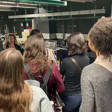 Amber McCreary giving a presentation in a lab to a group of female CUWiP attendees. 