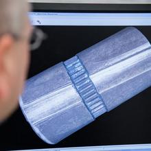 a man looking at a computer screen with a large image of one of the scanned Kennedy bullets