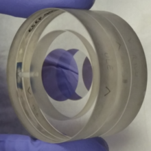 Gray cylinder two inches in diameter, held in gloved fingers