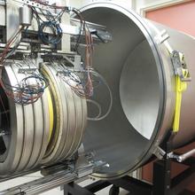 a large, hollow silver cylinder on a wheeled metal rack on the right, the guarded hot plate, another smaller cylinder festooned with wires that fits inside the larger cylinder is on the left