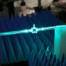 A glowing blue cylindrical rod has fibers coming out of either end. 