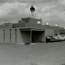 black and white photo of a low building with cars in front.
