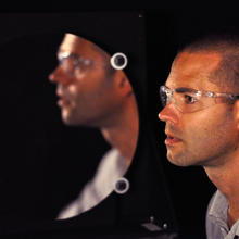 Man seen in profile in front of a circular mirror
