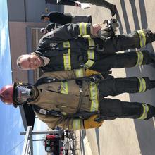 Person in firefighter gear stands with Dereck Orr outdoors