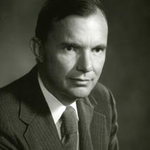 Black and white headshot-style portrait of a man in a suit.