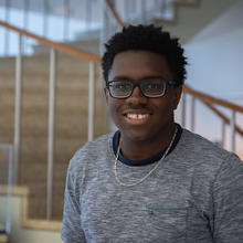 Miles Walker poses smiling in front of the spiral staircase in the NIST library. 
