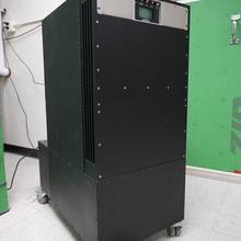 A rectangular black cabinet on wheels has a few switches and a small screen near the top. 