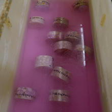 Labeled concrete samples lay in pink liquid inside a trough. 