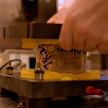 A concrete sample is sandwiched between two small platforms being held by a researcher. Wires lead away from the bottom platform. 