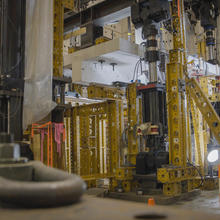 Horizontal concrete slab is visible in a forest of scaffolding and equipment in a large indoor space. 