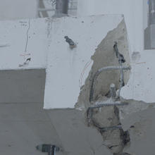 Close-up view of large crack in white concrete slab, with rebar showing.