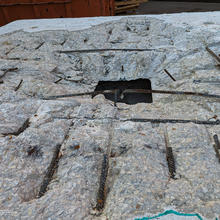 A slab of concrete has had the surface sheared off, exposing a grid of rebar and a center hole. 