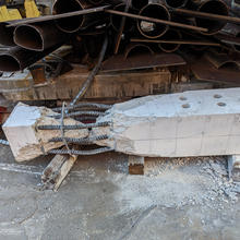 A broken concrete column lies on its side with a cracked portion where the rebar is exposed.