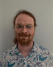 Man with a beard wearing a colorful shirt and glasses
