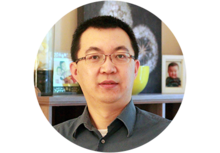 person with glasses standing in front of photographs