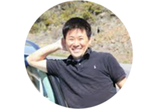 NIST's Shin Muramoto smiles for the camera while leaning against a car.