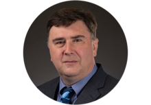 Bernard Kelm Headhsot, a man with short dark hair, wearing a suit and tie