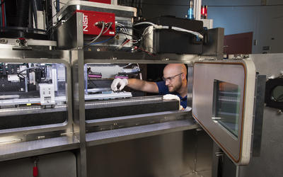 Researcher Brandon Lane making adjustments inside the large 3D printer