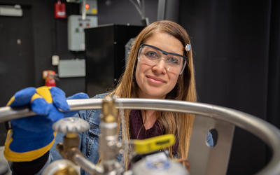 Maria Munoz poses in the lab, wearing safety goggles and heavy gloves. 