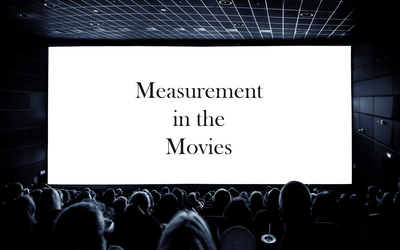 View from the back of a darkened movie theater shows the heads of the audience and a screen reading: Measurement in the Movies.