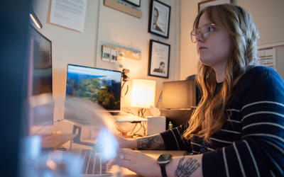 Sierra Miller sits at a desk facing a computer screen.
