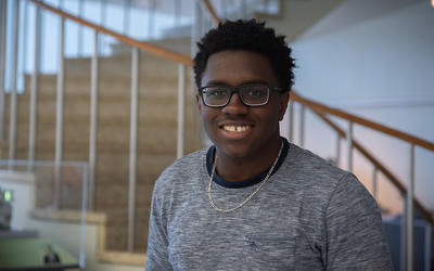 Miles Walker poses smiling in front of the spiral staircase in the NIST library. 