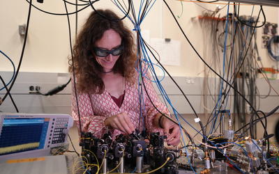 Esther Baumann leans over a lab table, surrounded with wires and scientific equipment.
