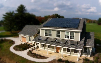 A newly built two-story home with an attached garage has solar panels on the roof.